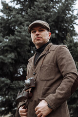 photographer with a retro camera in his hands. Dressed in retro style, jacket and cap - 417547201