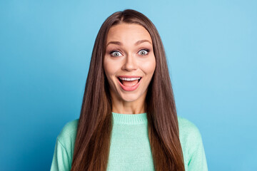 Photo portrait of smiling girl with wide open eyes in green pullover isolated on pastel blue colored background