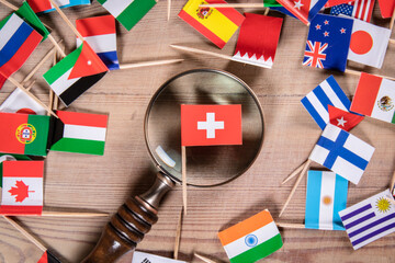 Swiss flag. Economic growth, Imports and Exports, Armaments and Security concept. Magnifying glass and flags of different countries