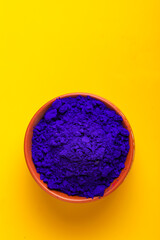 Blue holi powder in bowl isolated on yellow background