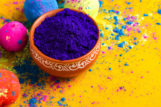 Blue holi powder in bowl isolated on yellow background © Niks Ads