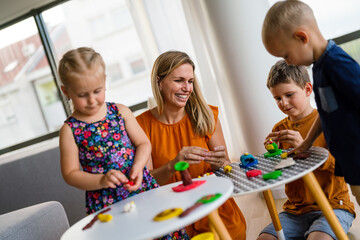 Kids playing with plasticine. Teacher or mother play with children. People, kid creativity concept
