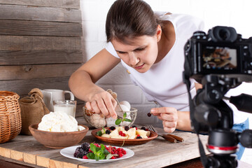 Professional food blogger taking pictures of pastry on table with camera. Female photographer...