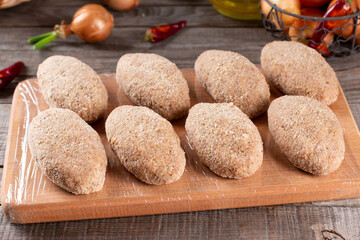 Frozen cutlets lie on a wooden board. Raw meat semi-finished products