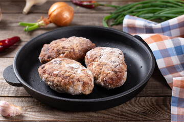 Semi finished frozen cutlets. Frozen cutlets in a frying pan. Concept of storing ready made dinner