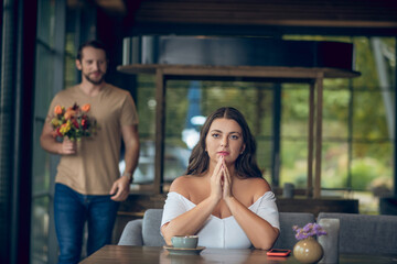 Woman sitting waiting and walking man with flowers