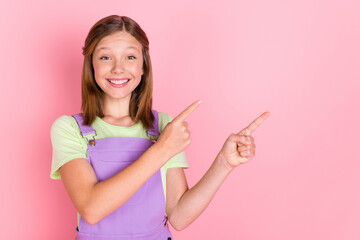Photo portrait of small girl smiling pointing fingers on copyspace advertising isolated on pastel...