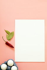 blank paper sheet on pink background with eggs and spices, mockup for recipe