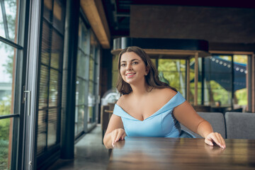 Joyful woman waiting for meeting in cafe