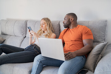 black man with laptop looking at blonde girl's cell phone