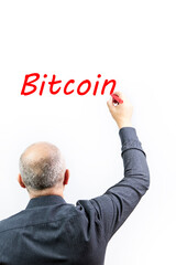Executive man writing the word Bitcoin with a red marker pen