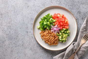 Not mixed salad of spelt with colorful vegetables on grey table. View from above. Space for text.