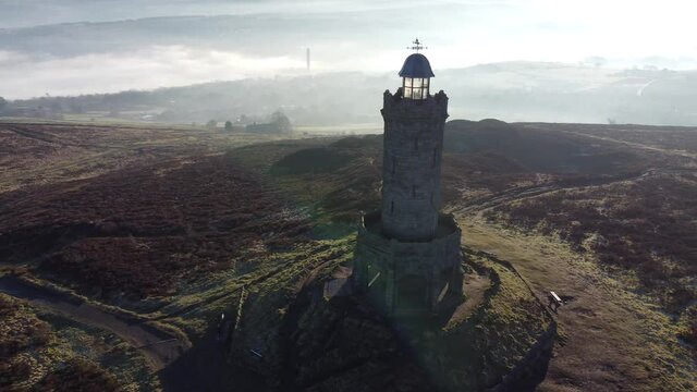 Darwen Jubilee tower Lancashire hillside misty valley moorland bright sunrise countryside aerial orbit left