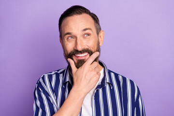 Photo of minded positive mature man touch hand chin look copyspace think thoughts isolated over violet color background