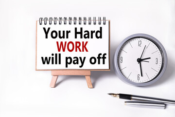 your hard work will pay off. text on white notepad paper on white background. near the table clock