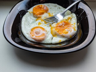 photo of fried eggs in a black plate on a white background.  food photo