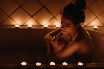 sexy nude woman smoking a cigarette sitting in the bath