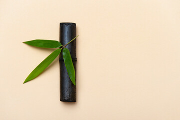 Bamboo activated charcoal stick and green leaf on beige background