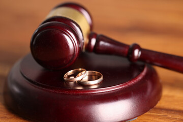 Closeup of judge hammer and wedding rings. Divorce proceedings concept