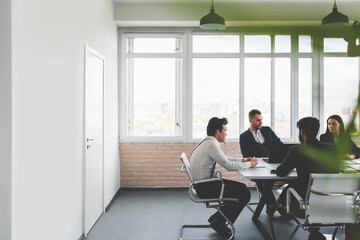 Fototapeta premium Group of young business people working and communicating while sitting at the office desk together with colleagues sitting. business meeting