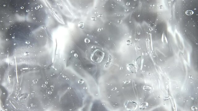 Transparent liquid gel background, clear serum texture. Motion, rotation of the beauty skincare product sample with bubbles. Top view. Macro Shot. High quality 4k footage