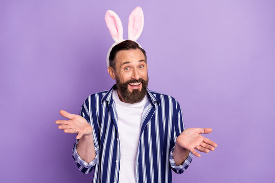 Photo of optimistic mature man in theme easter rabbit ears headband shrug shoulders isolated over violet color background