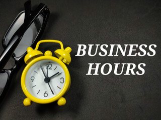 Business concept.Text BUSINESS HOURS on black background with glasses and clock.