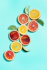Composition with slices citrus fruits, grapefruit, red orange, lemon, lime on turquoise. Summer food flat lay with daylight.