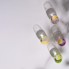 Colorful glasses with refreshing of water with slice of citrus inside on white background. Summer creative flat lay with hard shadows.