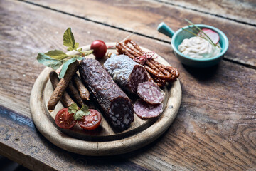 Collection of delicious meat delicatessens with vegetables on wooden plate