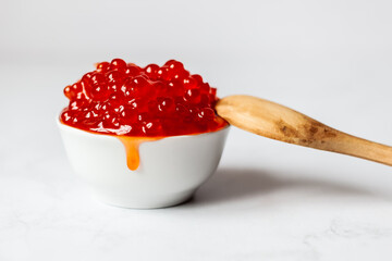 a wooden spoon rests on a white cup full of red caviar