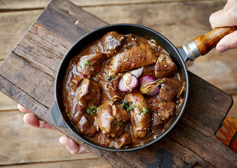 Faceless cook with tasty venison goulash in frying pan