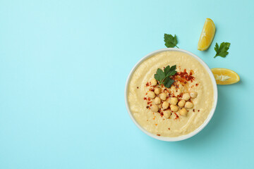 Bowl of hummus, lemon and parsley on blue background