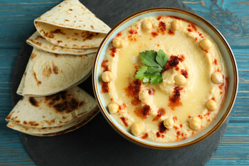 Tray with bowl of hummus and pita on wooden background