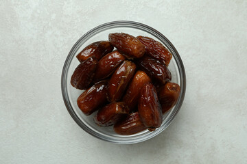 Glass bowl of dates on white textured background