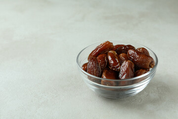 Glass bowl of dates on white textured background