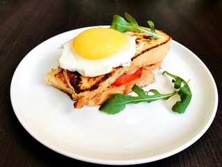 toast with cheese and meat on top of scrambled eggs with herbs