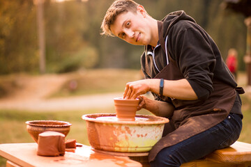 Man potter work with clay ware. Young handsome man potter on his workshop. 