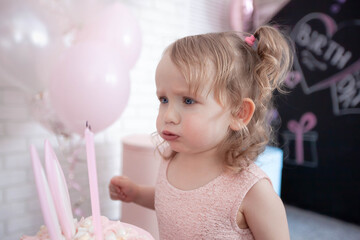 little girl blowing out burning candles on her birthday cake