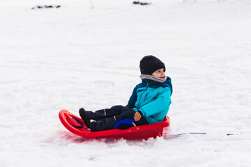 Fototapeta na wymiar boy with red sled in the snow