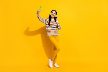 Fototapeta na wymiar Full size photo of young lovely pretty happy positive girl listen music take selfie on phone isolated on yellow color background