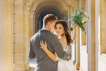 Amazing smiling wedding couple. Pretty bride and stylish groom posing and kisses. Romantic moment.