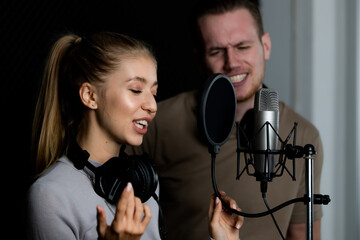 Young and beautiful and handsome male singers working together in voice recording studio with fun...