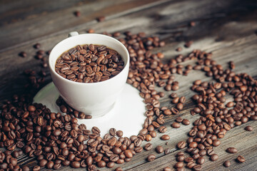 coffee beans on a wooden background and a cup on a saucer close-up macro photography