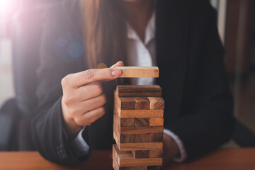 The businessman's hand is planning a business strategy, the businessman puts the wooden block on the tower,