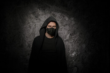 A man with with black mask on his face on a dark background in the studio