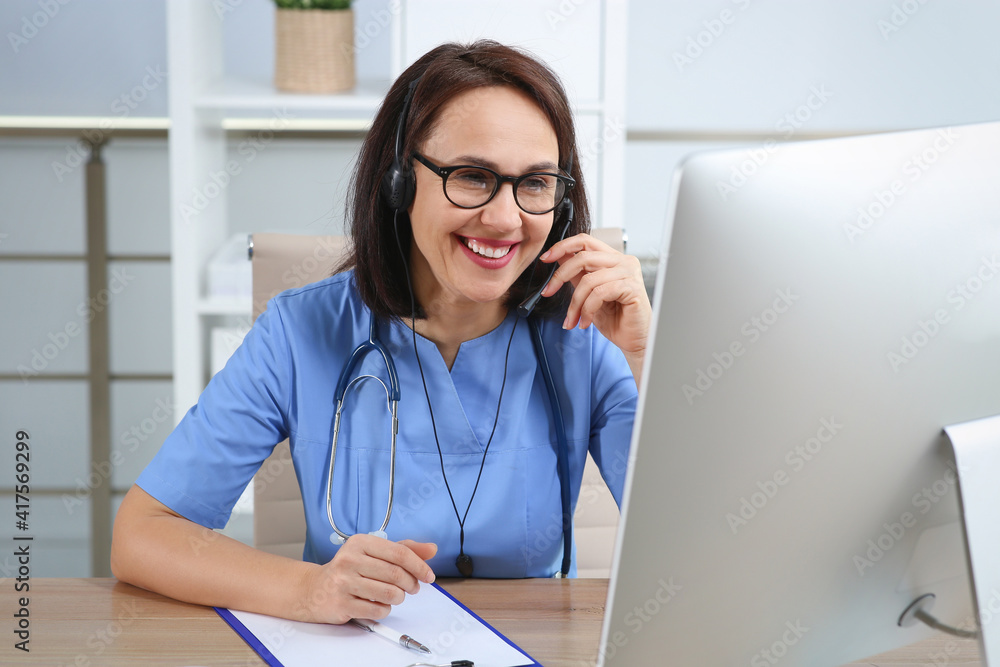 Poster Doctor with headset and computer consulting patient online in office. Hotline service