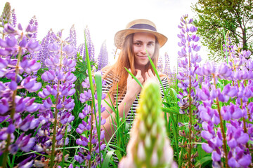 Beautiful young woman in hat  in lupine field