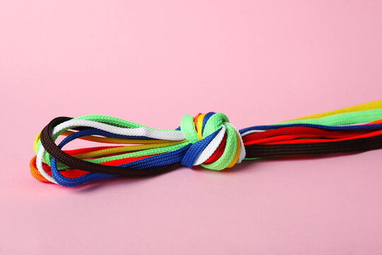 Many Colorful Shoe Laces Tied In Knot On Light Pink Background