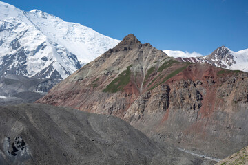 colourful rock formation in remote mountains with white glacier background 